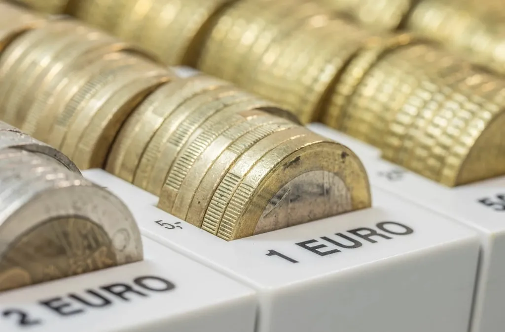 Close view of euro coins stacked in a cash tray with the 1 euro and 2 euro compartments labeled