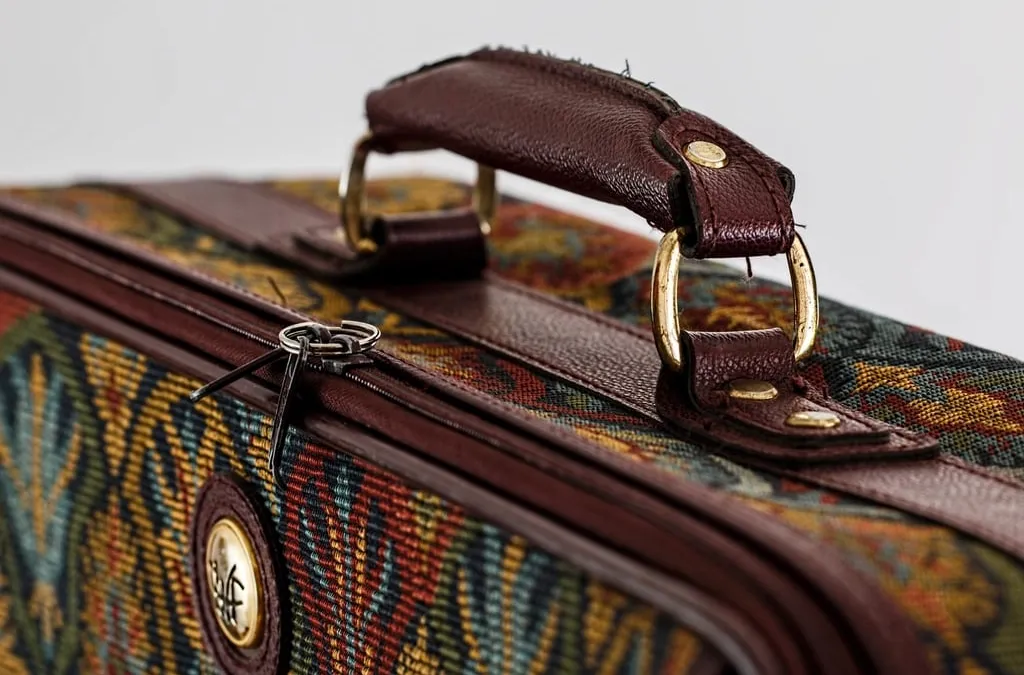 The leather handle and zipper of a vintage patterned suitcase