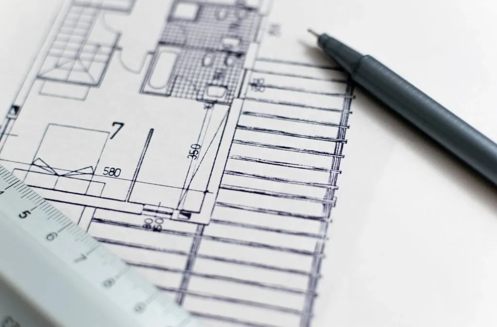 An architectural floor plan on a desk with a pen and a ruler