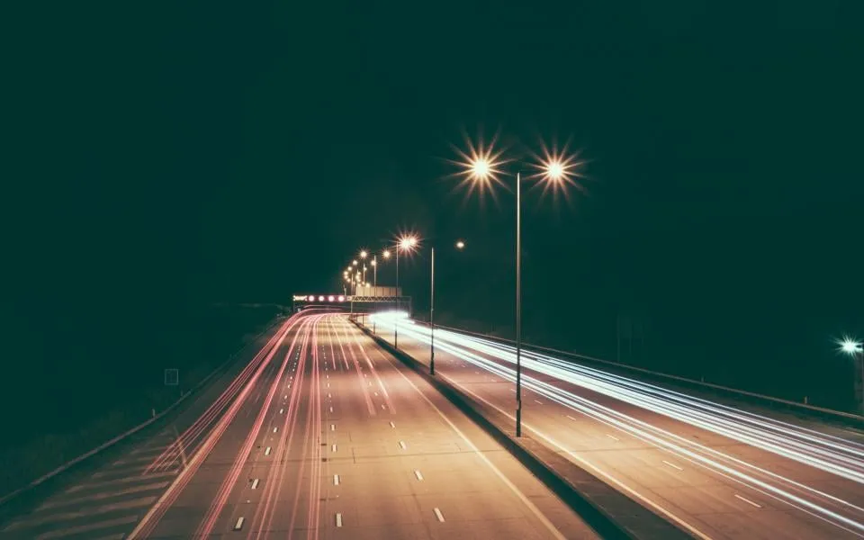 A multi-lane highway at night with light trails from passing traffic