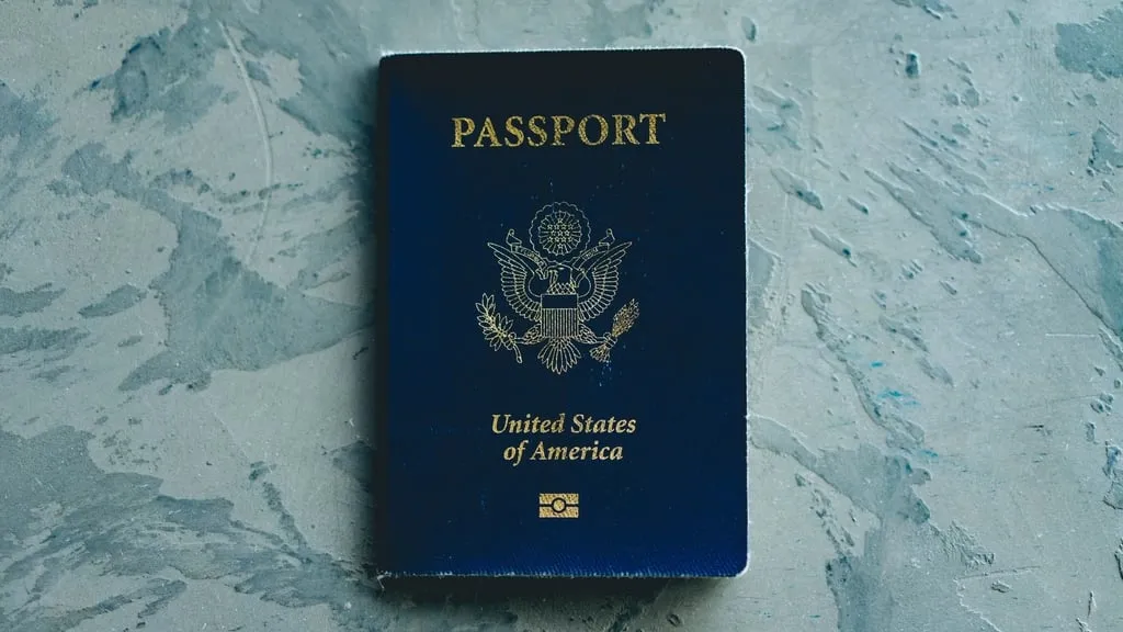 A United States passport lying flat on a pale gray textured surface