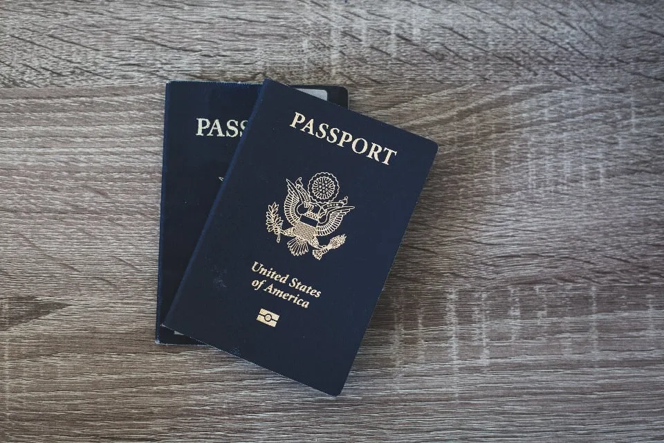 Two dark blue United States passports lying on a wooden table