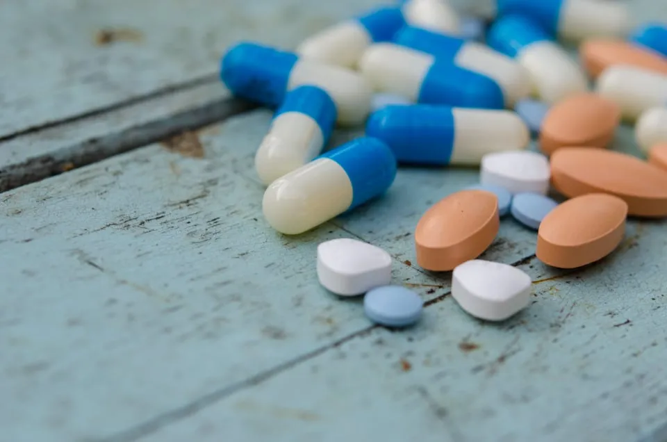 Capsules and tablets spread on a pale blue wooden surface
