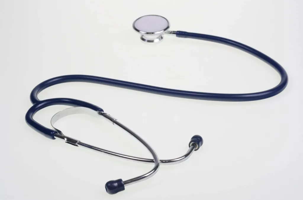 A stethoscope with a long dark blue tube lying on a white surface