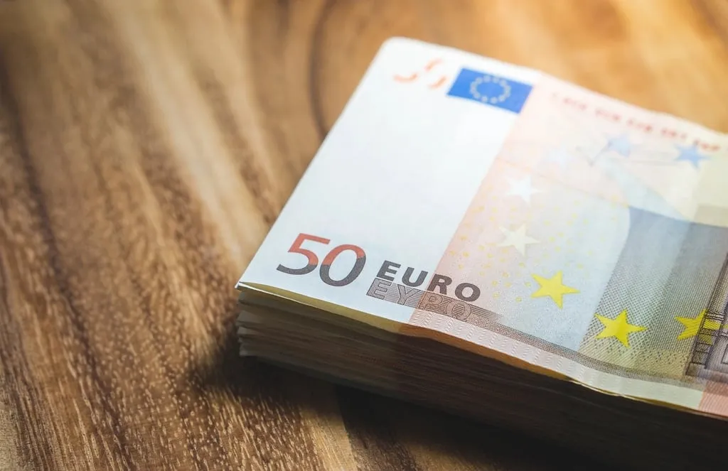 A stack of fifty euro banknotes on a wooden table