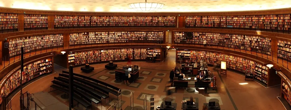 A circular library with tiers of bookshelves and reading desks
