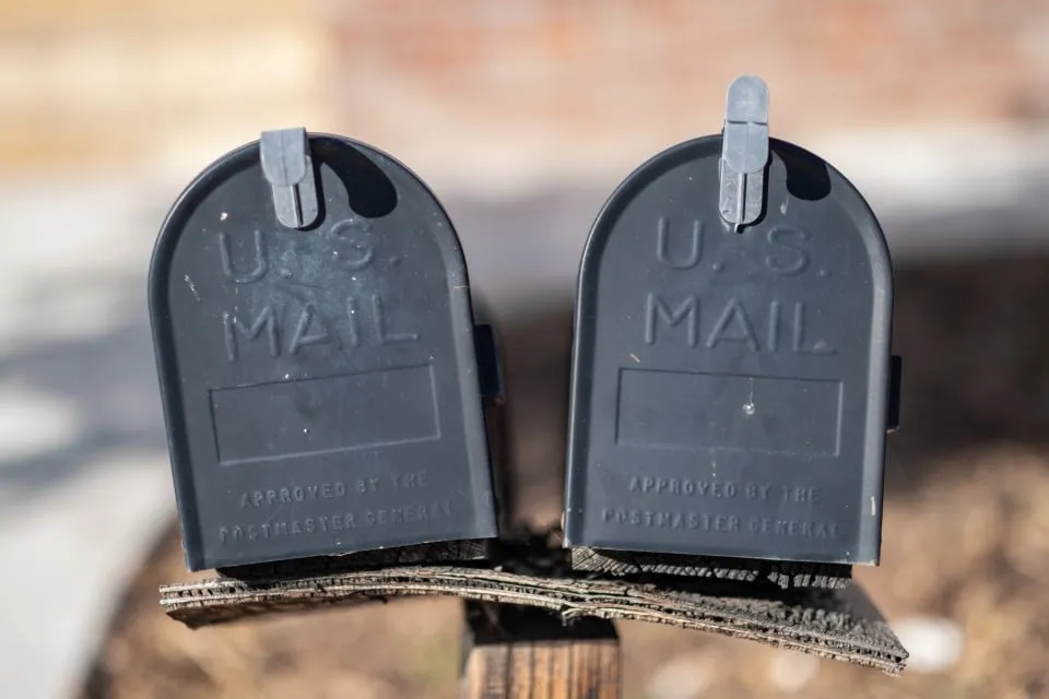 Two black U.S. mailboxes on a wooden post