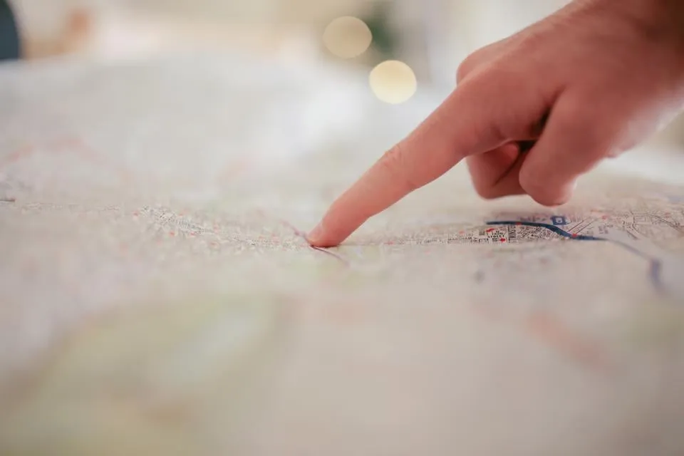 A finger pointing at a spot on a printed map